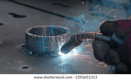 Close-up welding with sparks and metal ring. Creative. Welder welds metal ring with sparks. Sparks from welding with metal ring at factory or in forge