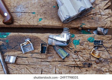 A close-up of a well-used wooden workbench, splattered with paint, showcasing various small metal tube wringers. The scene hints at the creative process, with art supplies scattered around - Powered by Shutterstock