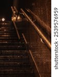 Close-up of wet, illuminated railings on a dark stairway with reflective surfaces, creating a moody and cinematic scene after rain.
