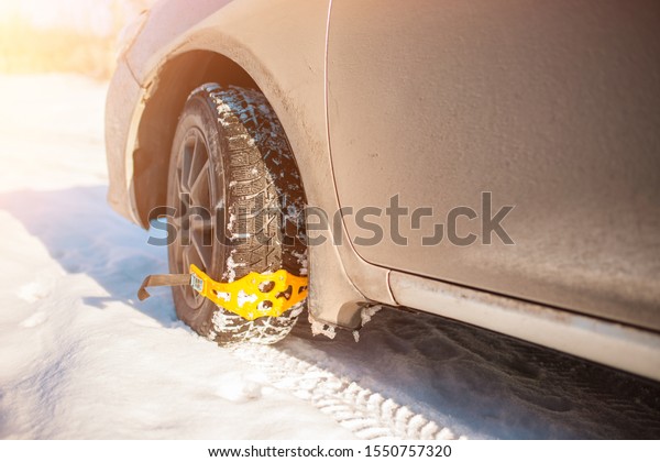 Close-up of a wheel. mounted on the snow wheel of a\
car yellow chains anti-slip. dangerous road, hard to ride in the\
snow