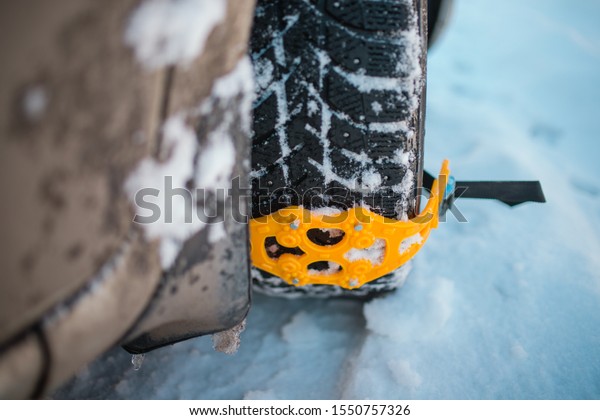 Close-up of a wheel. mounted on the snow wheel of a
car yellow chains anti-slip. dangerous road, hard to ride in the
snow