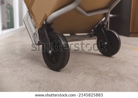 Closeup of the wheels of a 2 wheel foldable portable trolley. Action shot with a cardboard box package.