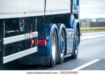 A closeup of wheels in motion from an articulated lorry, traveling along a UK motorway.
