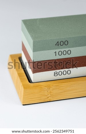 closeup white background on table lies red and green equipment a set for sharpening and polishing kitchen knives and various blades different abrasiveness of stone retainer for knives