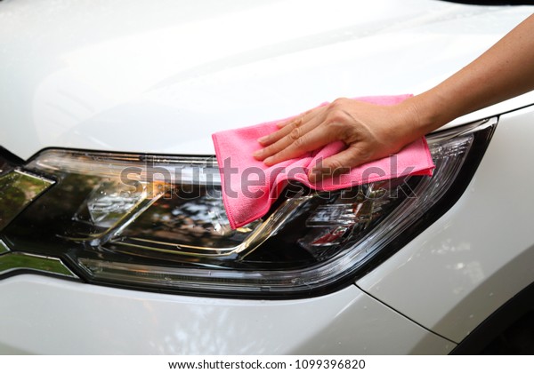 Closeup of white car cleaning  with pink\
microfiber cloth by woman owner\'s hand in sunny day. The simply\
family activity and\
lifestyle.