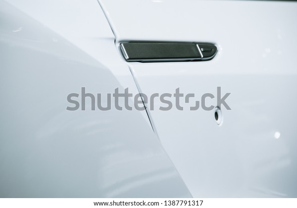 Closeup of white car door\
handle.