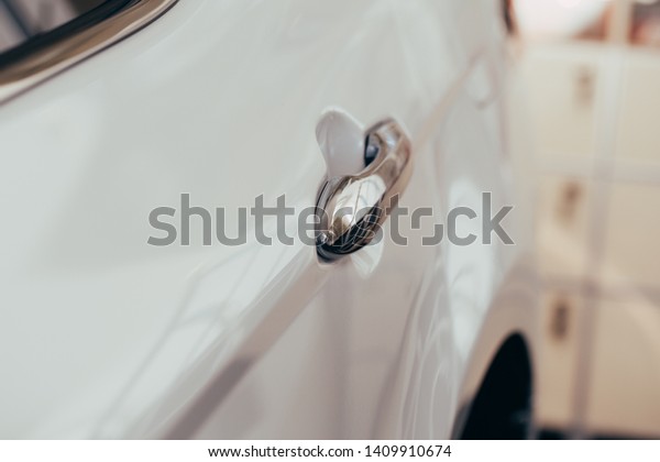 Closeup of white car door\
handle 