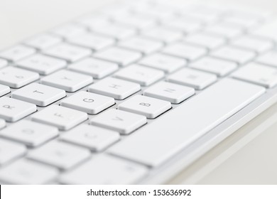A close-up of a white computer keyboard on a white background