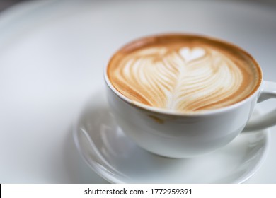 Closeup Of White Cup Of Hot Coffee Latte With Milk Foam Heart Shape Art With Dirty Lip Marks On White Table.