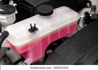 Close-up White Expansion Tank With Pink Antifreeze. Car Coolant Level In Radiator System In Car, Automotive Part. 