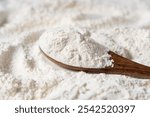 Close-up of white flour and wooden spoon background.