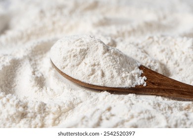 Close-up of white flour and wooden spoon background.