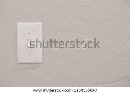 a closeup of a white light switch flipped or toggle turned to off position on a gray wall background, energy conservation connection or disconnection or waste concept, horizontal shot, copy text space