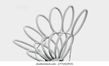 Close-up of a white metal loop structure forming a repetitive circular pattern against a clean sky background.