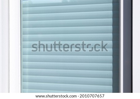 Closeup of a white oller shutter behing glass.