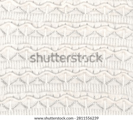 Close-up of white openwork knitted lace with repeating scalloped horizontal bands.