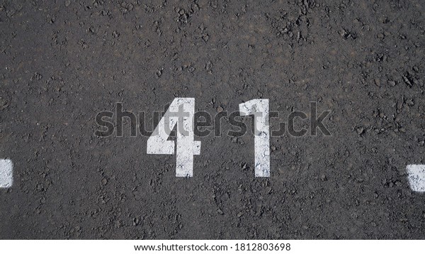Close-up of a white paint number\
marking in a parking lot. Empty parking lot, Parking lot with white\
mark, Open parking in public park. Number 41, top\
view