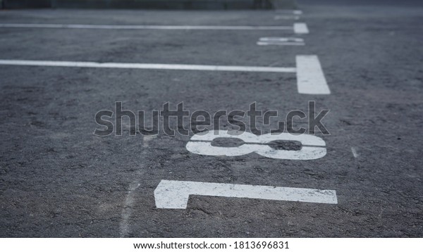 Close-up of a white paint number marking in a\
parking lot. Empty parking lot, Parking lot with white mark, Open\
parking in public park. Number\
18