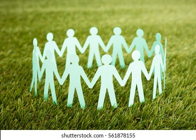 Close-up Of White Papercut Of People Chain On Grass