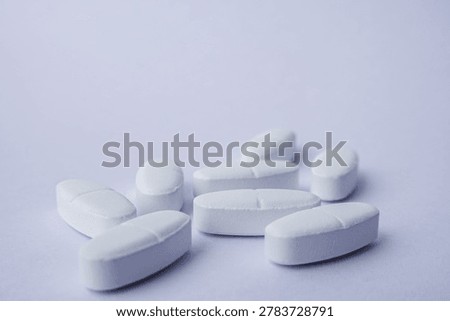 Close-up of White pharmaceutical tablets placed on a soft purple background. Medical and healthcare concept representing medication, treatment, pharmacy, antibiotics, pain relief, and modern pharmaceutical industry with minimal stayle and copy space.