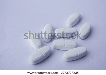 Close-up of White pharmaceutical tablets placed on a soft purple background. Medical and healthcare concept representing medication, treatment, pharmacy, antibiotics, pain relief, and modern pharmaceutical industry with minimal stayle and copy space.
