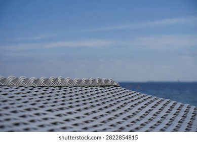 Close-up of the white plastic wickerwork of a beach chair against the blue sea of the Baltic Sea                            