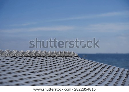 Close-up of the white plastic wickerwork of a beach chair against the blue sea of the Baltic Sea                            