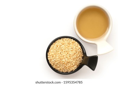 Closeup White Sesame Oil With Sesame Seeds In Black And White Ceramics Bowl Isolated On White Background. Overhead View. Flat Lay. 