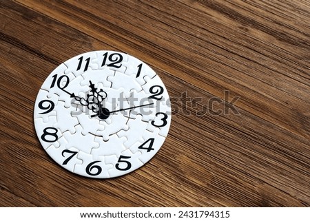 Close-up of a white timepiece puzzle set on a wooden background with copy space. Creative time related concept.