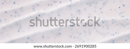 Close-up of white toothpaste with blue specks and textured ridges.