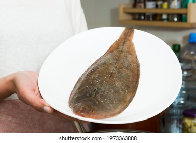 Closeup Of Whole Fresh Black Sole Fish On Plate In Hands Of Woman..