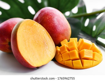 Close-up of whole, half and freshly sliced juicy Mango fruit on background of green tropical palm leaf - Powered by Shutterstock