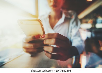 Closeup Wide-angle View Of The Hands With A Red Nails Of Afro Girl Sitting In In Cafe Indoors Next To A Window On A Sunny Day And Texting A Message To Her Family; Multiple Chromatic Aberrations Around