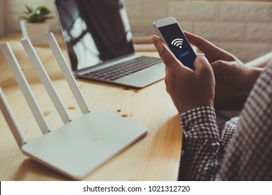 closeup of a wifi router and a man using smartphone on living room at home ofiice