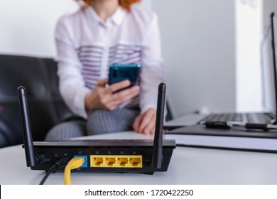 Closeup Of A Wifi Router And A Redhead Woman Using Smartphone On Living Room At Home Ofiice