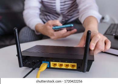 Closeup Of A Wifi Router And A Woman Using Smartphone On Living Room At Home Ofiice