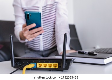 Closeup Of A Wifi Router And A Woman Using Smartphone On Living Room At Home Ofiice