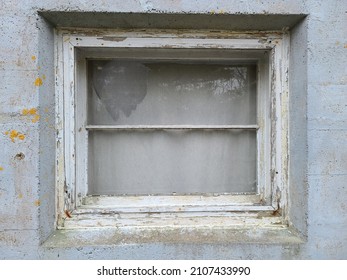 A Closeup Of A Window With The Screen Ripped Out. The Window Frame Is Rotted And The White Paint Is Chipping.