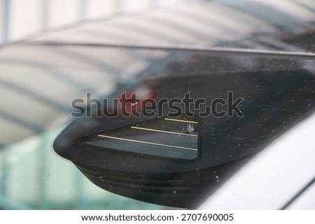 Close-up of windshield-mounted ADAS camera sensor module behind the mirror, used for lane-keeping and safety automotive tech detail.
