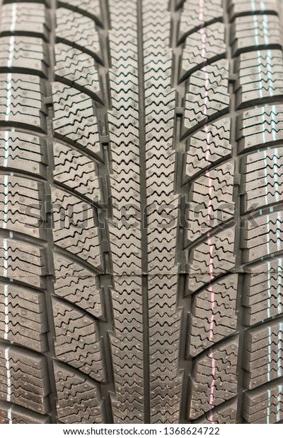 Close-up winter tire\
tread. Textured tire tread. Part of brand new modern winter car\
tire. vertical photo
