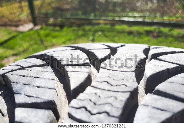 Close-up winter tire tread. Textured tire\
tread on green and bokeh\
background.