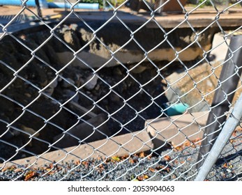 A Closeup Of Wire Fencing As It Protects People From Falling Into A Torn Up Hole In A Street. The Gate Is Blocking Off The Hazardous Area.