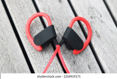 Closeup Wireless Bluetooth Over The Neck Red Black Ear Hook Earphones On Wood