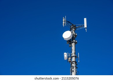 Closeup Of Wireless Cell Site Antennas On A Monopole Tower Against A Clear Blue Sky
