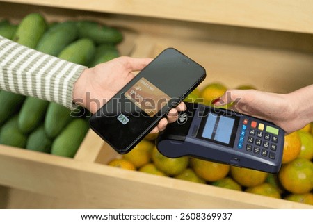 Closeup of wireless phone payment using digital wallet app during contactless transaction at tropical fruit store showing seamless financial experience in modern small business