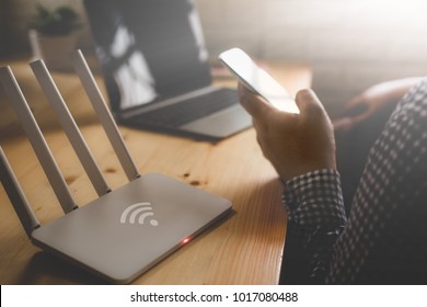 closeup of a wireless router and a man using smartphone on living room at home ofiice - Shutterstock ID 1017080488