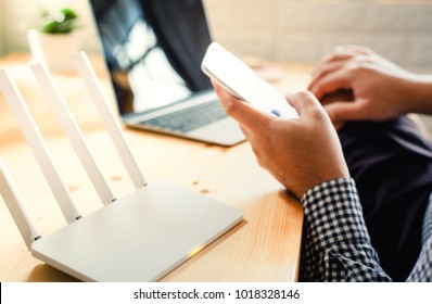 closeup of a wireless router and a man using smartphone on living room at home ofiice