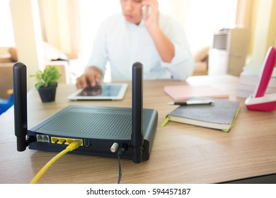 closeup of a wireless router and a man using smart-phone on living room at home ofiice