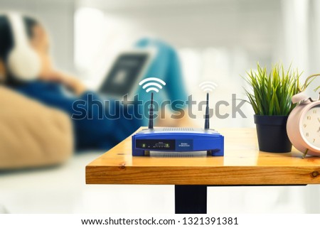 closeup of a wireless router and a man using smartphone on living room at home ofiice