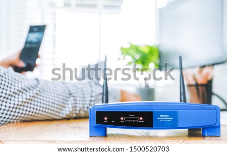 closeup of a wireless router and a man using smartphone on living room at home ofiice 